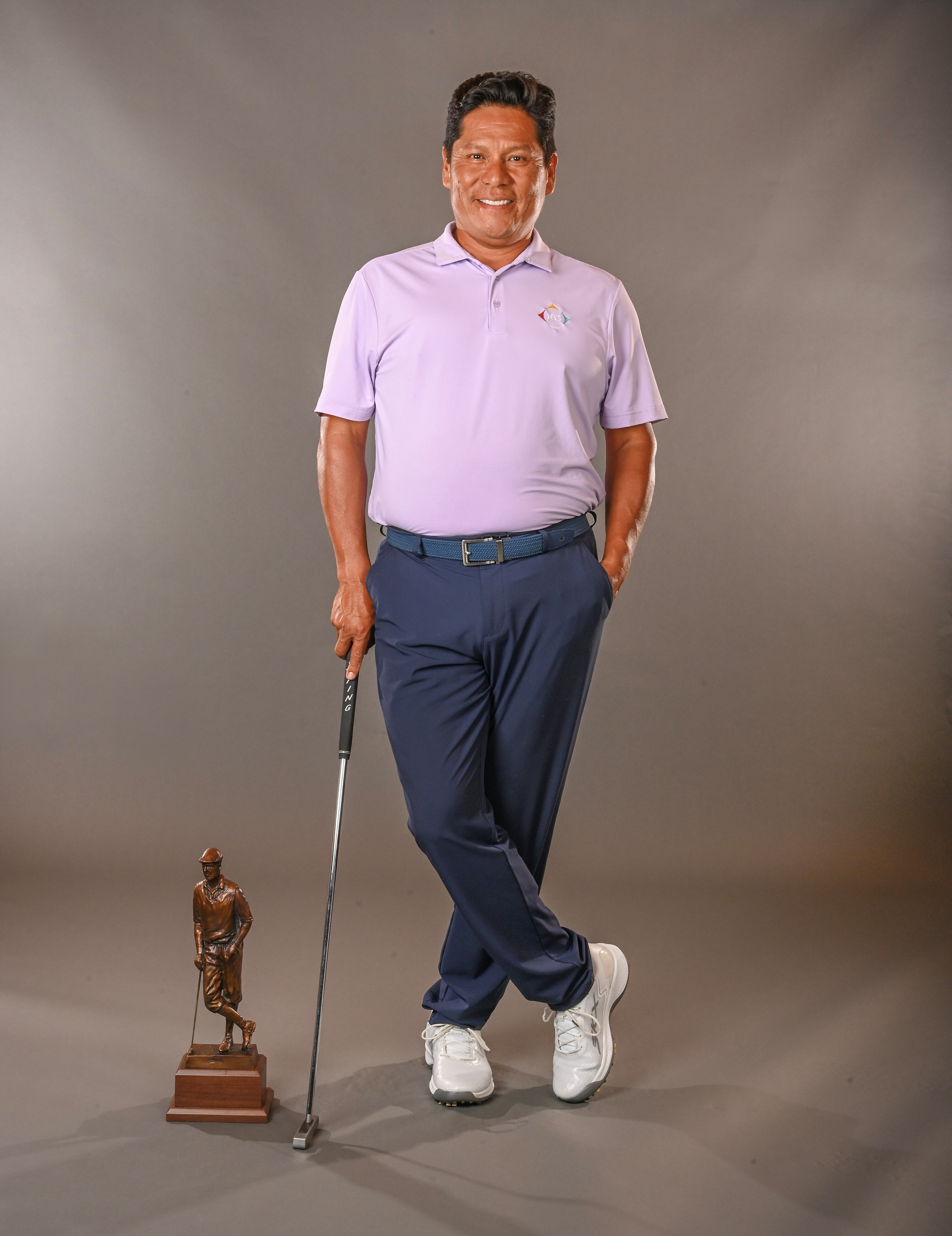 Notah Begay III standing and posing with Payne Stewart Award trophy